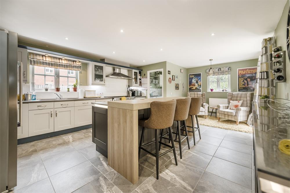 Image of the kitchen in a house for Sale with COleman Estates. Olive coloured walls with cream cabinets and a large breakfast bar and worksurface island in the middle of the kitchen in a light wood colour.