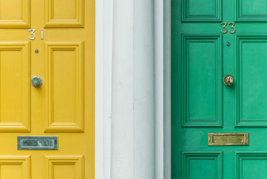 Two front doors, one painted bright yellow, one bright green. The one on the left is number 31 and the one on the right is number 33