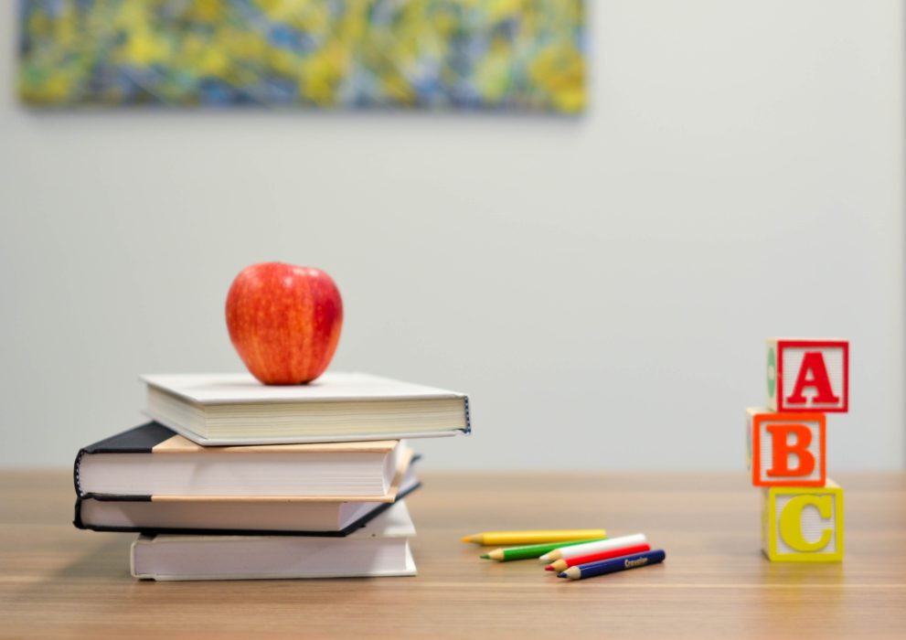 Red apple on stack of books next to wooden blocks with A B C on them