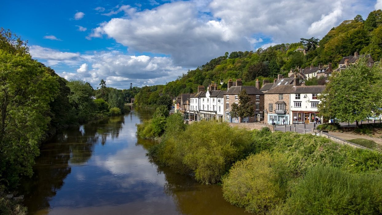 image of Ironbridge next to the river Severn with green trees either side and building next to the river