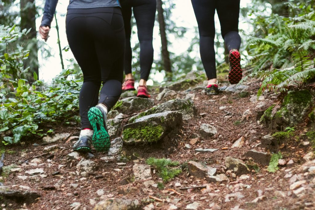 Image of three people in activewear and trainers walking in the woods